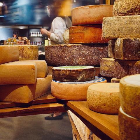 Stacks of cheese rounds on a wooden shelf.